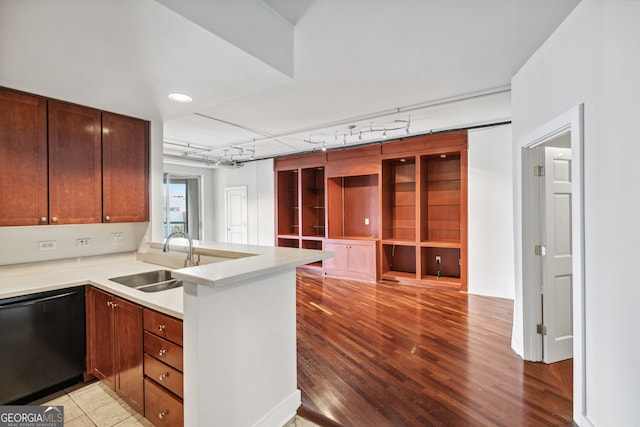 kitchen with track lighting, black dishwasher, sink, light hardwood / wood-style floors, and kitchen peninsula