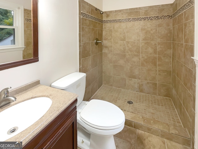 bathroom with toilet, vanity, and tiled shower