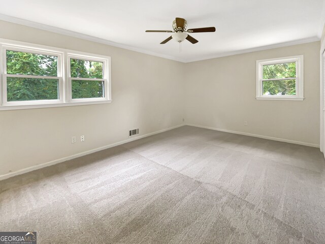 unfurnished room featuring ornamental molding, a healthy amount of sunlight, carpet, and ceiling fan