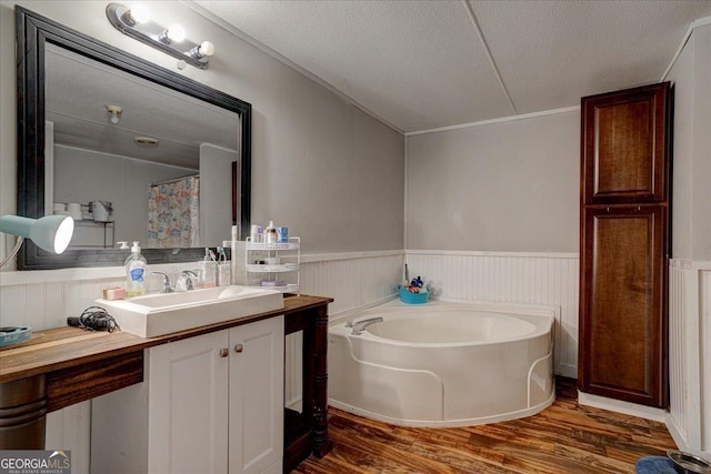 bathroom featuring vanity, wood-type flooring, a bath, and a textured ceiling