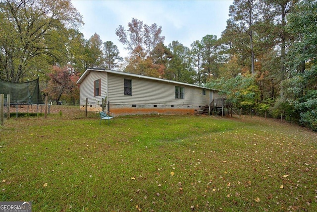 back of property with a yard and a trampoline