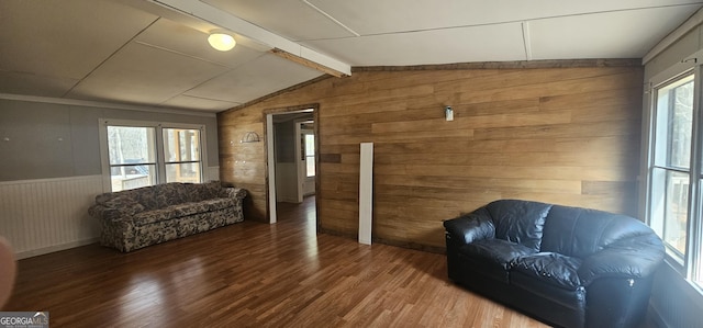 sitting room featuring hardwood / wood-style flooring, wood walls, and vaulted ceiling with beams