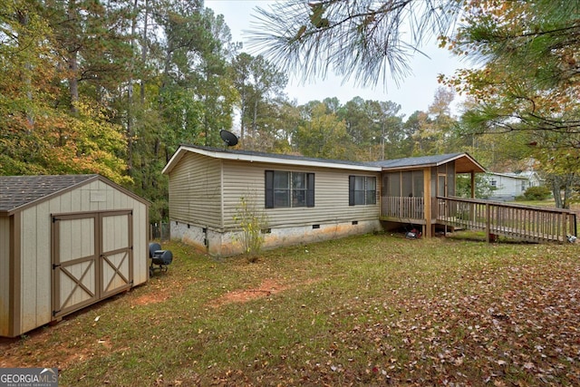 back of property with a storage unit, a lawn, a sunroom, and a deck