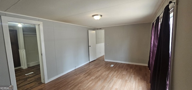 unfurnished bedroom featuring crown molding and wood-type flooring