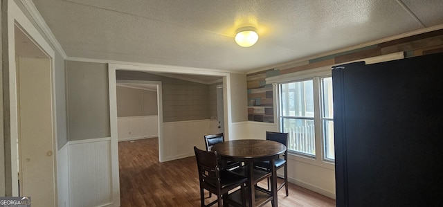 dining space featuring wood-type flooring, crown molding, and a textured ceiling