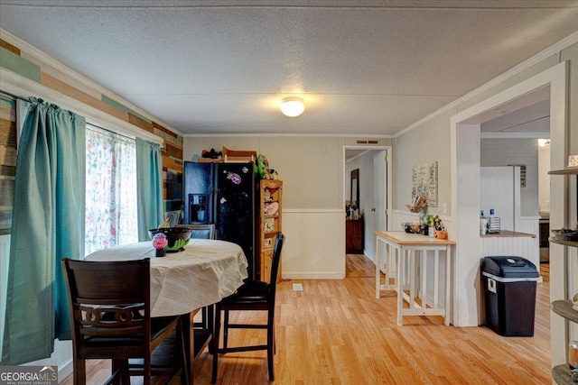 dining area featuring ornamental molding, light hardwood / wood-style floors, and a textured ceiling