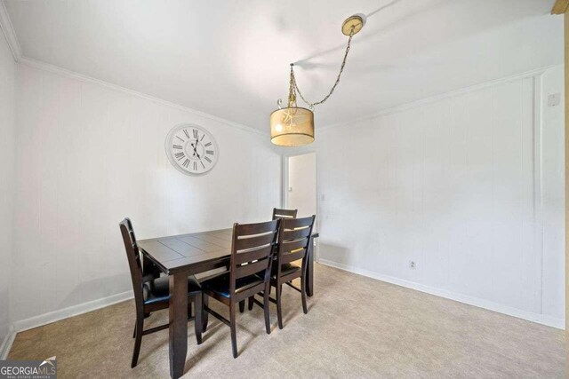 dining space featuring ornamental molding and light colored carpet