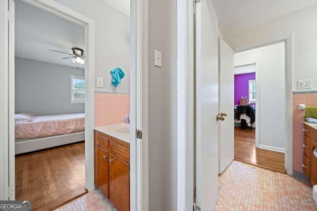 bathroom with vanity, ceiling fan, wood-type flooring, and tile walls