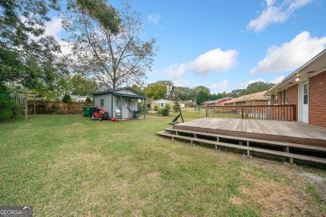 view of yard featuring a wooden deck and a storage shed