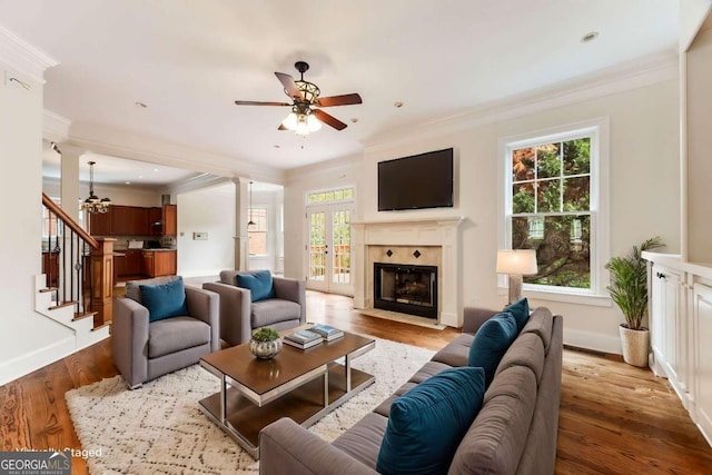 living room with crown molding, a healthy amount of sunlight, and light wood-type flooring