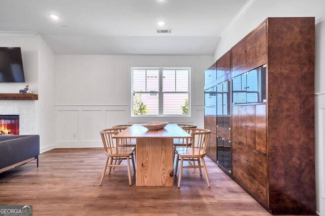 dining space featuring crown molding, a fireplace, and hardwood / wood-style flooring