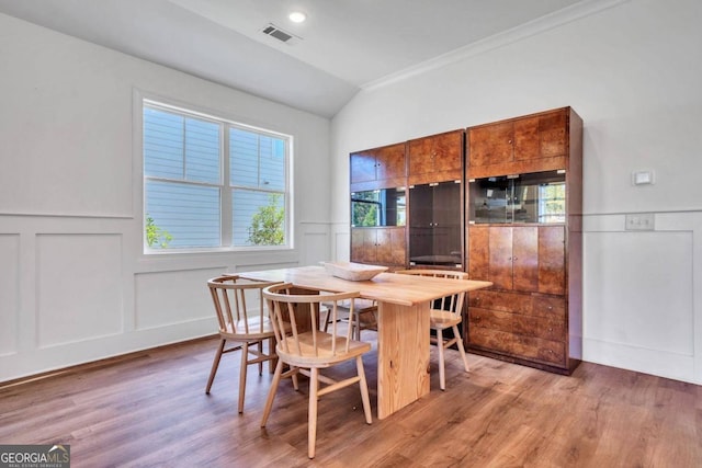 dining room with lofted ceiling, ornamental molding, and hardwood / wood-style flooring