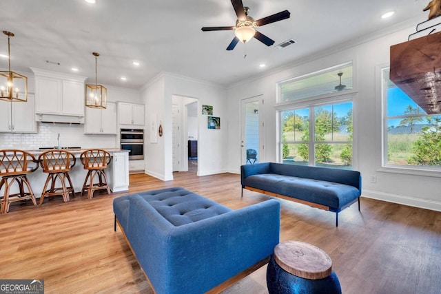 living room with sink, light hardwood / wood-style flooring, crown molding, and ceiling fan