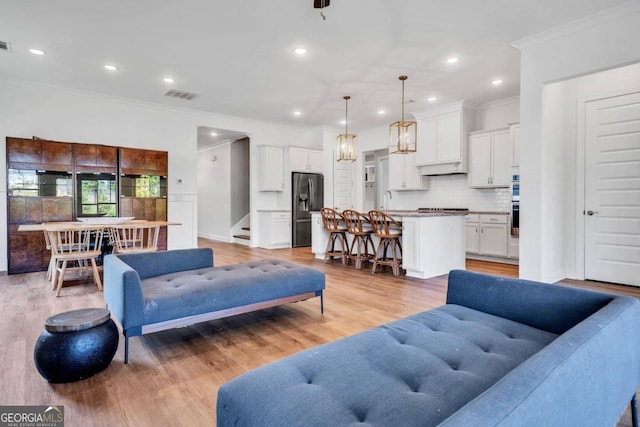 living room featuring light hardwood / wood-style floors, ornamental molding, and sink