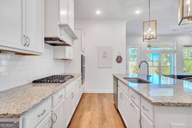 kitchen with a center island with sink, sink, hanging light fixtures, and stainless steel appliances