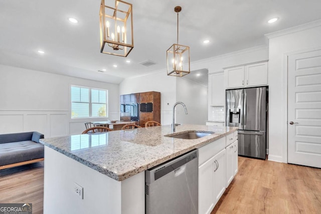 kitchen with a kitchen island with sink, hanging light fixtures, stainless steel appliances, sink, and white cabinetry