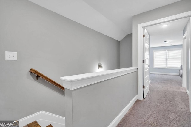 corridor with lofted ceiling and light colored carpet