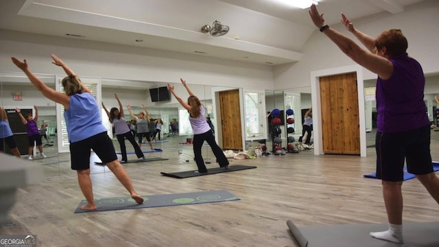 workout room with high vaulted ceiling and light wood-type flooring