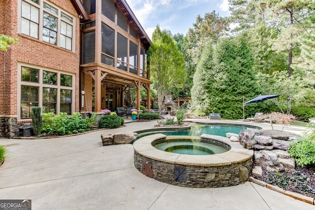 view of pool featuring an in ground hot tub, a sunroom, and a patio