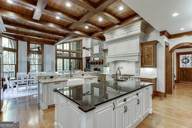 kitchen featuring white cabinetry, an island with sink, sink, and wooden ceiling