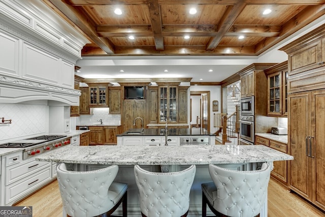 kitchen with a large island with sink, a breakfast bar, built in appliances, and wooden ceiling