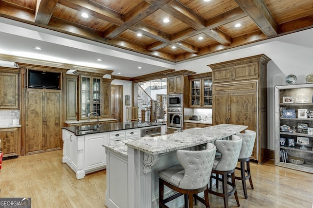 kitchen featuring a large island, sink, wood ceiling, appliances with stainless steel finishes, and white cabinets