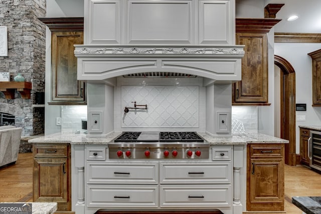 kitchen with tasteful backsplash, white cabinetry, light stone countertops, and stainless steel gas stovetop