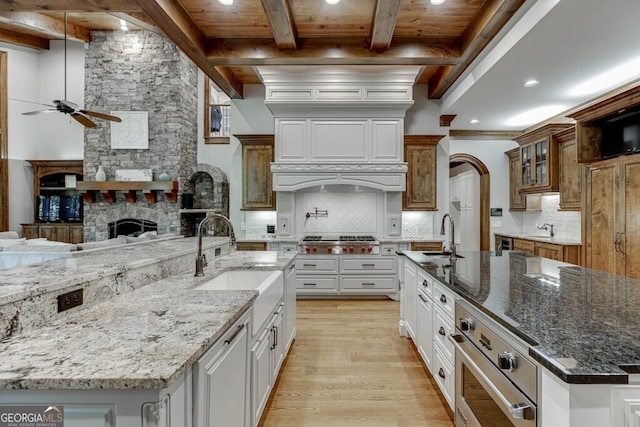 kitchen with a large island with sink, white cabinetry, dark stone counters, and decorative backsplash