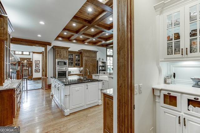 kitchen featuring coffered ceiling, a kitchen island, beamed ceiling, stainless steel appliances, and white cabinets