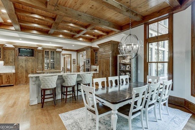 dining space with beamed ceiling, coffered ceiling, a notable chandelier, wood ceiling, and light hardwood / wood-style floors