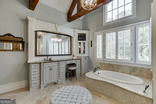 bathroom with an inviting chandelier, vanity, vaulted ceiling with beams, and tiled bath