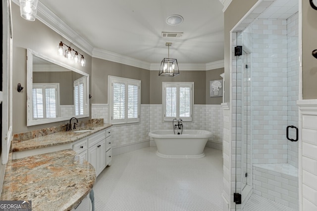 bathroom with tile patterned floors, crown molding, separate shower and tub, tile walls, and vanity