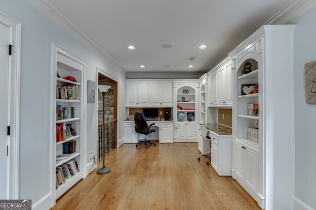 office space with crown molding, built in desk, built in features, and light hardwood / wood-style floors