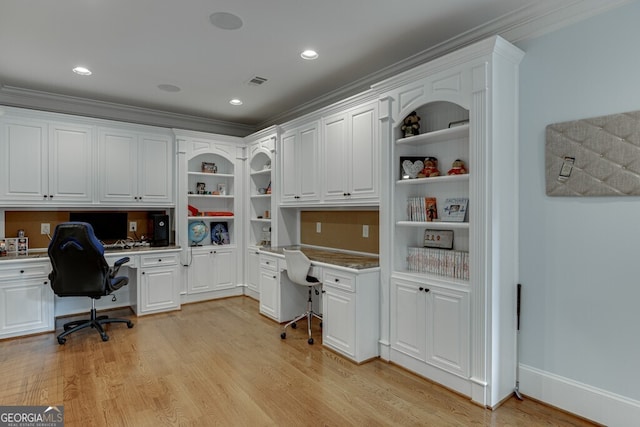 office with light hardwood / wood-style flooring, built in desk, and ornamental molding