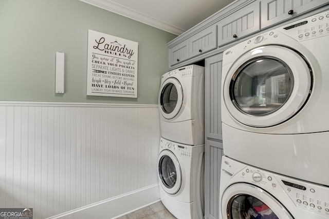 laundry room featuring stacked washing maching and dryer, ornamental molding, and light tile patterned flooring