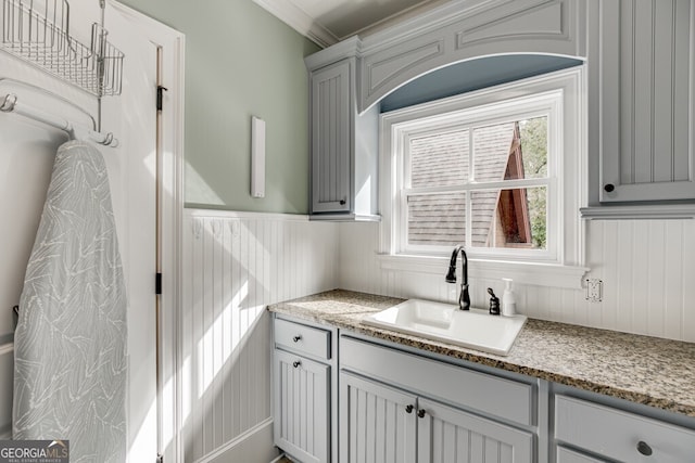 kitchen featuring crown molding, sink, and light stone counters