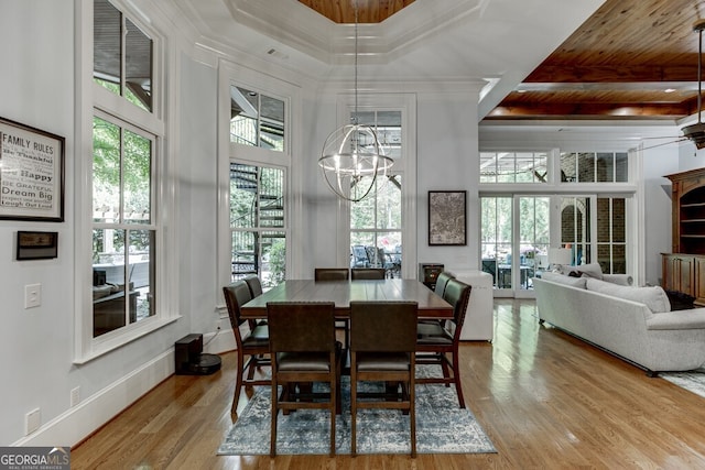 dining area featuring crown molding, an inviting chandelier, light hardwood / wood-style floors, and a high ceiling