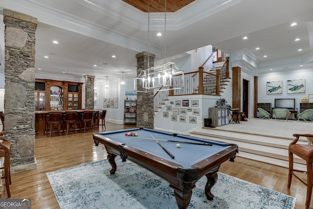 game room with ornate columns, crown molding, bar area, and light hardwood / wood-style flooring