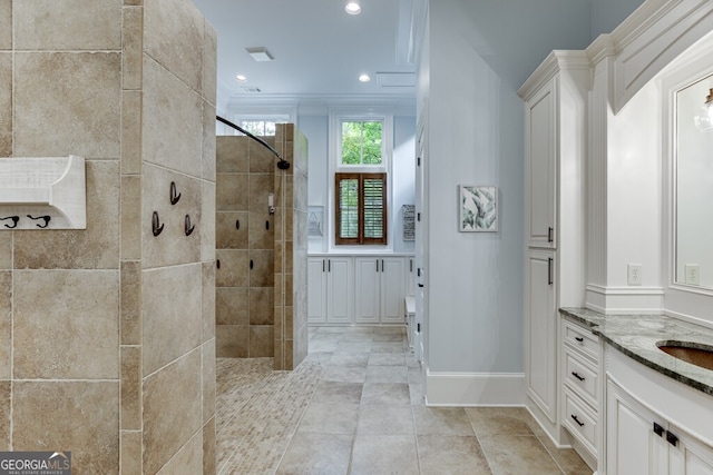 bathroom with vanity, tiled shower, and ornamental molding