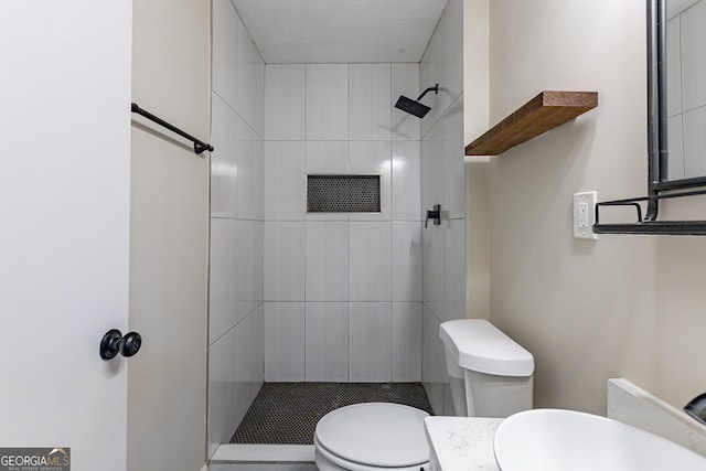 bathroom featuring vanity, toilet, and tiled shower