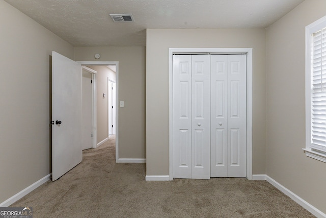 unfurnished bedroom featuring light carpet, multiple windows, and a closet