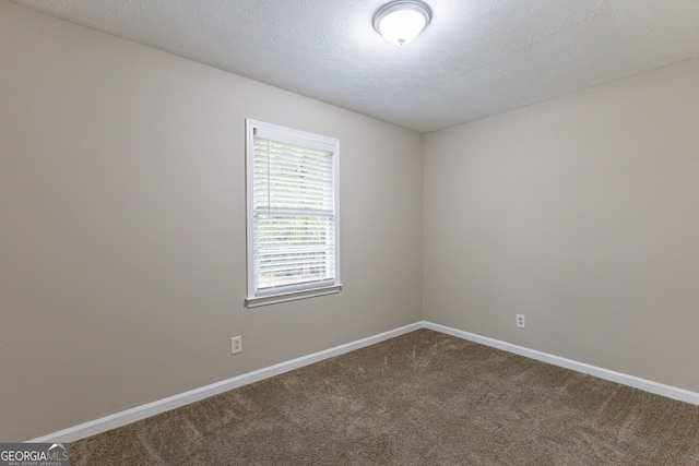 carpeted empty room featuring a textured ceiling