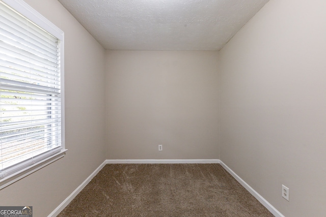 carpeted empty room featuring a textured ceiling