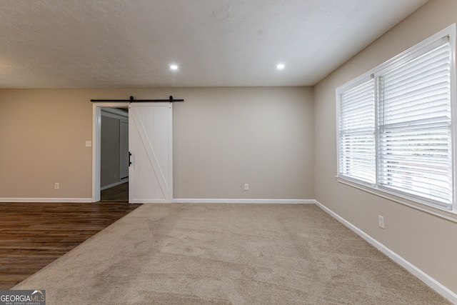 spare room with a wealth of natural light, a barn door, and hardwood / wood-style floors