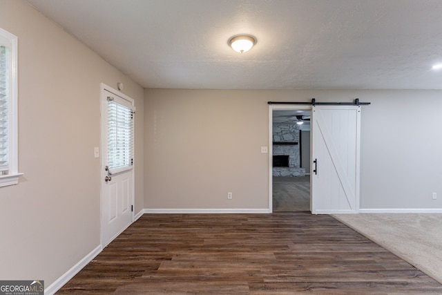 unfurnished room with dark wood-type flooring, a barn door, and a textured ceiling