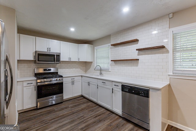 kitchen with dark wood-type flooring, stainless steel appliances, sink, white cabinets, and tasteful backsplash