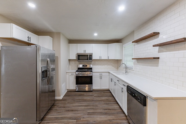 kitchen featuring dark wood-type flooring, sink, white cabinets, appliances with stainless steel finishes, and tasteful backsplash