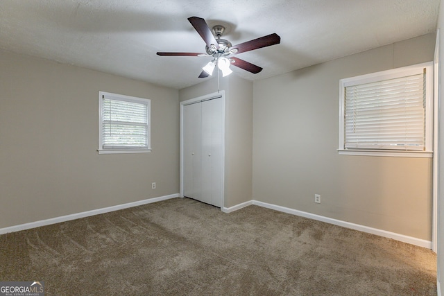 unfurnished bedroom with a closet, a textured ceiling, carpet flooring, and ceiling fan