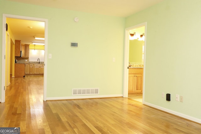 empty room featuring sink and light hardwood / wood-style floors