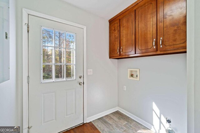 laundry room featuring washer hookup, light wood-type flooring, and cabinets